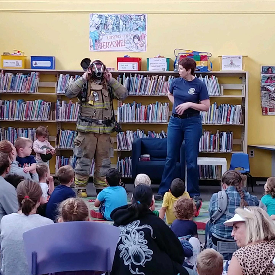 A program for children where they are watching a firefighter.